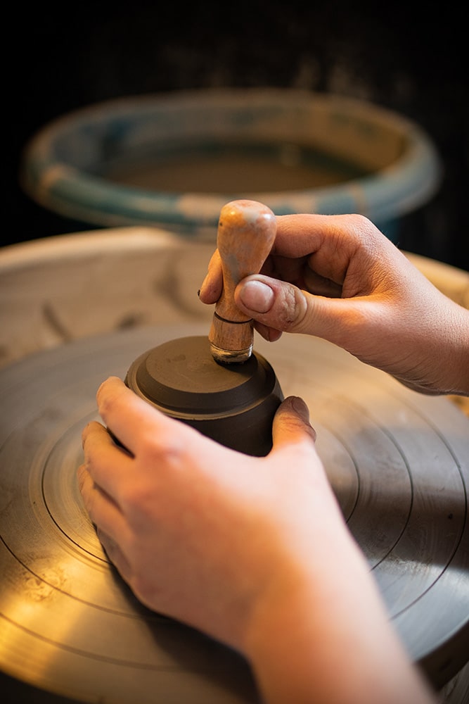 Les mains de Manon Renault, céramiste près de Doué en Anjou et Saumur, en train d'apposer son tampon signature sur ses pièces en céramique artisanale, photographiée dans son atelier par Margot Vincent alias Margotine Photographies, photographe près d'Angers dans le maine-et-loire