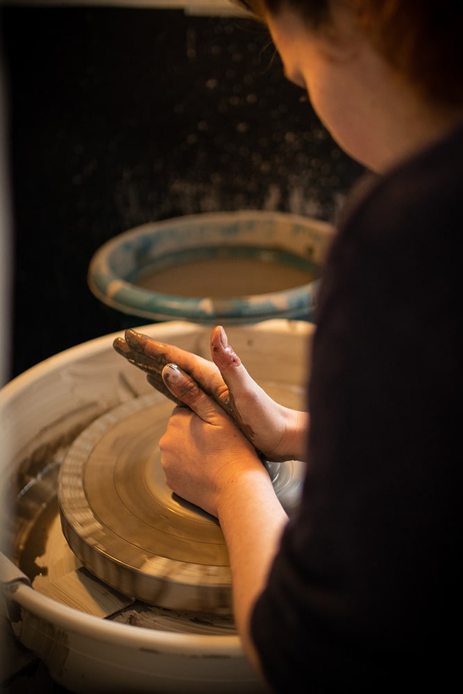 Les mains de Manon Renault, céramiste près de Doué en Anjou et Saumur, en train de confectionner ses pièces en céramique artisanale sur un tour, photographiée dans son atelier par Margot Vincent alias Margotine Photographies, photographe près d'Angers dans le maine-et-loire