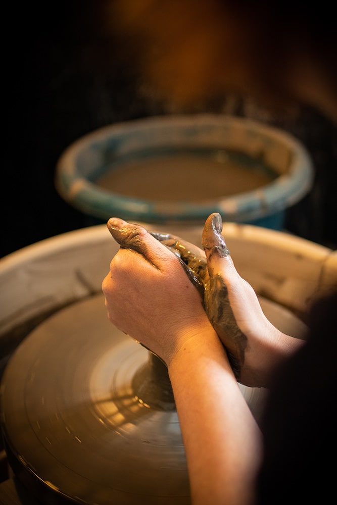 Les mains de Manon Renault, céramiste près de Doué en Anjou et Saumur, en train de confectionner ses pièces en céramique artisanale sur un tour, photographiée dans son atelier par Margot Vincent alias Margotine Photographies, photographe près d'Angers dans le maine-et-loire