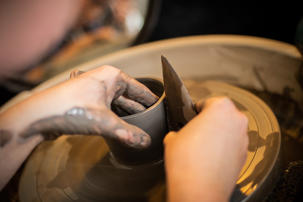 Les mains de Manon Renault, céramiste près de Doué en Anjou et Saumur, en train de confectionner ses pièces en céramique artisanale sur un tour, photographiée dans son atelier par Margot Vincent alias Margotine Photographies, photographe près d'Angers dans le maine-et-loire