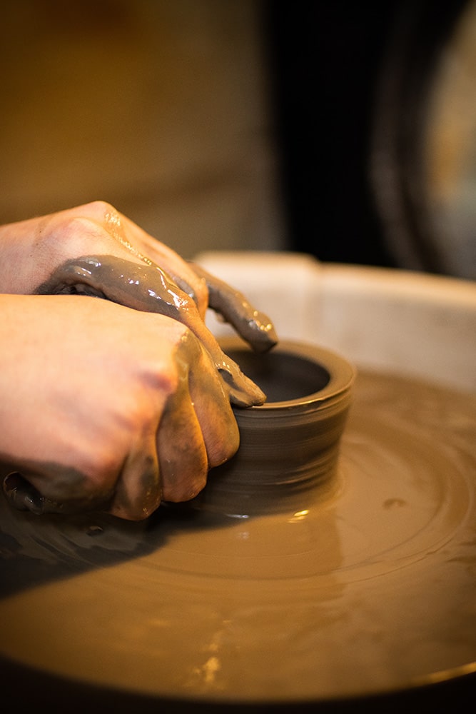 Les mains de Manon Renault, céramiste près de Doué en Anjou et Saumur, en train de confectionner ses pièces en céramique artisanale sur un tour, photographiée dans son atelier par Margot Vincent alias Margotine Photographies, photographe près d'Angers dans le maine-et-loire