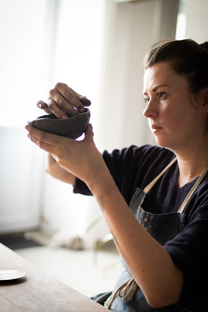 Manon Renault, céramiste près de Doué en Anjou et Saumur, en train de modeler ses pièces en céramique artisanale, photographiée dans son atelier par Margot Vincent alias Margotine Photographies, photographe près d'Angers dans le maine-et-loire