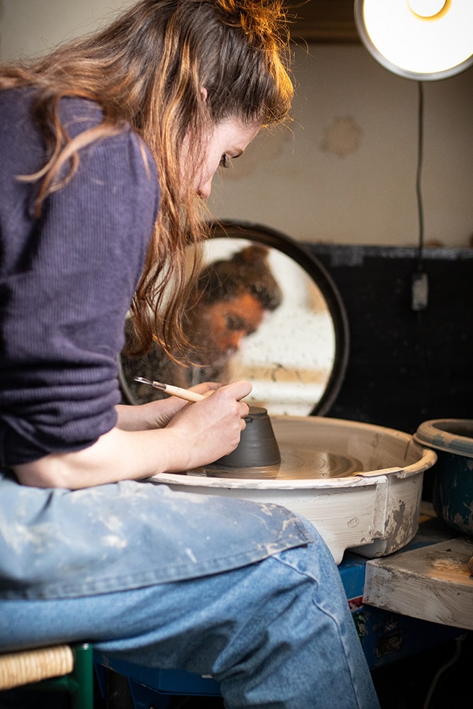 Manon Renault, céramiste près de Doué en Anjou et Saumur, en train de confectionner ses pièces en céramique artisanale sur un tour, photographiée dans son atelier par Margot Vincent alias Margotine Photographies, photographe près d'Angers dans le maine-et-loire