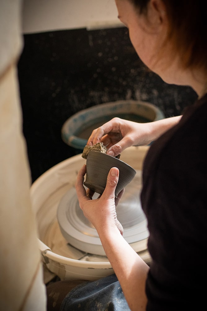 Les mains de Manon Renault, céramiste près de Doué en Anjou et Saumur, en train de confectionner ses pièces en céramique artisanale sur un tour, photographiée dans son atelier par Margot Vincent alias Margotine Photographies, photographe près d'Angers dans le maine-et-loire