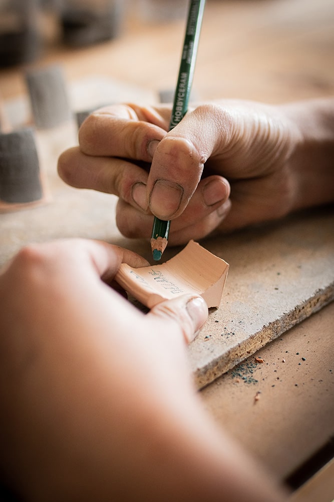 Essai et recherche de recette sur des fragments de poterie pour la confection d'un émail artisanal et naturel à base d'ardoise pour la céramique réalisée par Manon Renault, céramiste près de Doué en Anjou et Saumur photographié dans son atelier par Margot Vincent alias Margotine Photographies, photographe près d'Angers dans le maine-et-loire