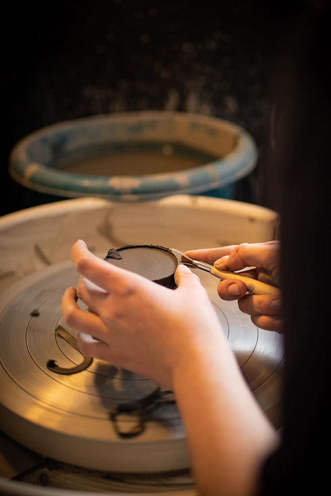 Les mains de Manon Renault, céramiste près de Doué en Anjou et Saumur, en train de confectionner ses pièces en céramique artisanale sur un tour, photographiée dans son atelier par Margot Vincent alias Margotine Photographies, photographe près d'Angers dans le maine-et-loire